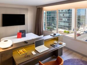 a hotel room with a desk with a laptop and a window at Novotel Campo De Las Naciones in Madrid +188 photos
