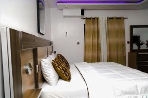 a bedroom with a bed with white sheets and gold pillows at Dakar meublée in Dakar