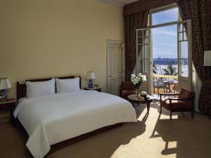 a bedroom with a large white bed and a large window at Sofitel Winter Palace Luxor in Luxor