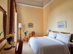 a hotel room with a large white bed and a desk at Sofitel Winter Palace Luxor in Luxor +145 photos