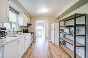 a kitchen with white cabinets and a black shelf at Nest in the Orchard--cozy room in Toronto