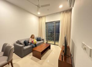 a woman sitting on a couch in a living room at Colombo Stay - Skyview Retreat in Colombo
