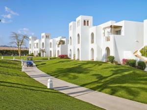 a large white building with a green lawn at Hotel Novotel Sharm El-Sheikh in Sharm El Sheikh