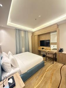a bedroom with a bed and a desk and a television at فندق أثير بارك in Jazan