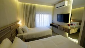 a hotel room with two beds and a flat screen tv at Harmony City Hotel - Jerusalem in Jerusalem