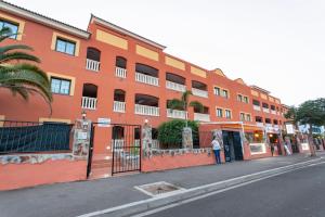 Una mujer parada frente a un edificio naranja. en Obsidian Aquarela Costa Adeje, en Adeje