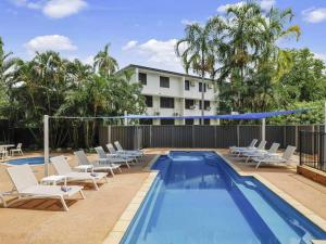 a pool with lounge chairs and a hotel in the background at Novotel Darwin CBD in Darwin