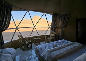 a bedroom with a large window with a view of the desert at Catalina Luxury rum camp in Wadi Rum