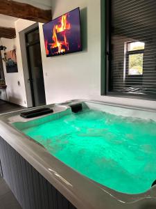 Prestige House & Spa في Auvilliers: يوجد حوض جاكوزي في غرفة مع تلفزيون