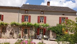 an old house with red shuttered windows and a yard at Grand gîte pour 18 personnes dans la campagne tarnaise in Andouque