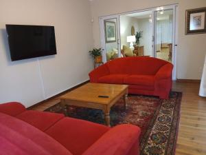 a living room with two red couches and a tv at Dayspring Cottage in Howick