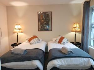 two twin beds in a room with two lamps at Dayspring Cottage in Howick
