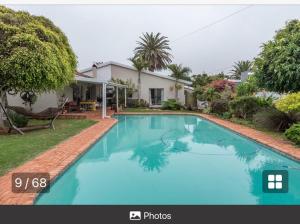 a large blue swimming pool in front of a house at PJ Guest House in Gqeberha