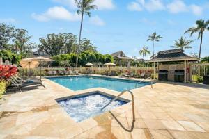 a swimming pool in a yard with a fence and palm trees at Modern studio, AC, king bed, private lanai in Princeville