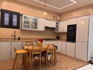 una cocina con armarios blancos y una mesa y sillas de madera. en شاليه خيال, en Sanāw