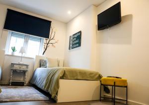 a bedroom with a bed and a tv on the wall at Castelo Terrace Apartement in Leiria