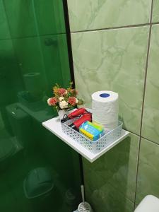 a shelf in a bathroom with toilet paper and flowers at Casa Amora - 2 Quartos in Pomerode