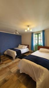 a bedroom with two beds and a blue wall at hotel Mountain Dream Resort El Cocuy in El Cocuy