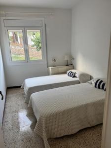 two beds in a white room with a window at La Cantonada in Port de la Selva