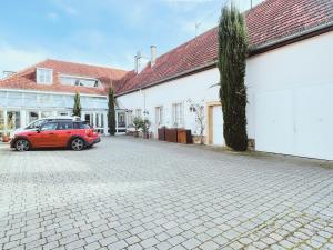une voiture rouge garée devant un bâtiment dans l'établissement Zenkoje - Ihr Ferienzuhause in der Pfalz!, à Neustadt an der Weinstraße