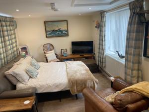a bedroom with a bed and a couch and a television at Hope Corner in Filey