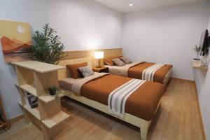 a bedroom with two beds and a table with a plant at Good Day House บ้านพักนครพนม ริมแม่น้ำโขง in Nakhon Phanom