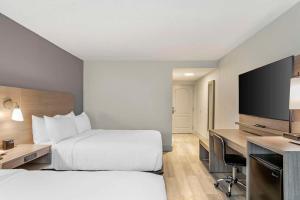 a hotel room with two beds and a desk and a television at The Angler Hotel Livingston, an Ascend Collection Hotel in Livingston