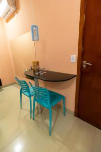 een eetkamer met een tafel en twee blauwe stoelen bij Rodotel Vênus Prime in Acreúna