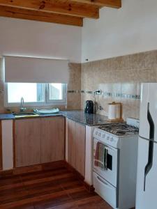 a kitchen with a stove and a white refrigerator at La Chabela 02 in Trevelín +4 photos