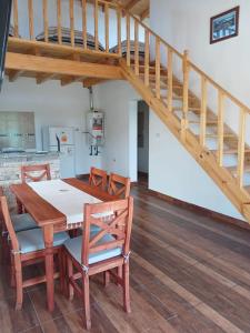 a dining room with a wooden table and a staircase at La Chabela 02 in Trevelín