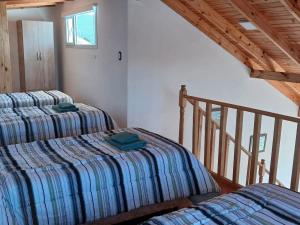two twin beds in a room with a staircase at La Chabela 02 in Trevelín