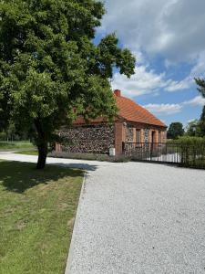 ein Backsteinhaus mit einem Baum und einer Auffahrt in der Unterkunft Agroturystyka Polanka 