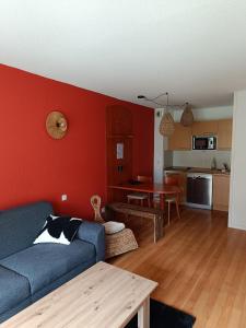 Un cocon en plein cœur de la Mongie في لا مونجي: غرفة معيشة مع أريكة زرقاء وجدار احمر