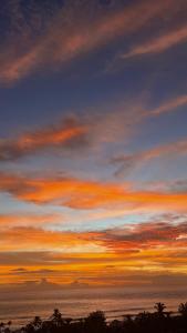 a sunset over the ocean with a cloudy sky at Cocon Romantique in Saint-Gilles les Bains