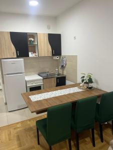 a kitchen with a wooden table and green chairs at Stan na dan - Apartman Genex 