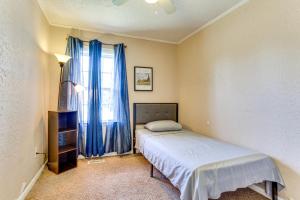 a bedroom with a bed and a window with blue curtains at 2 Mi to Fort Sill Quiet Family Retreat with Yard in Lawton
