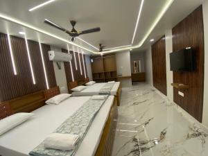 a room with three beds and a tv on a marble floor at Fraydel Homestay in Honāvar