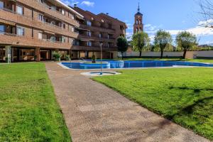 un bâtiment avec une piscine et une tour de l'horloge dans l'établissement BaruHaus triplex piscina y parking, à Villamañán