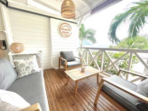 a balcony with a couch and a chair and a table at La p’tite barque Antillaise in Deshaies