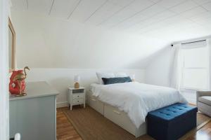 a white bedroom with a bed with a blue stool at Stay at East Gloucester in Gloucester