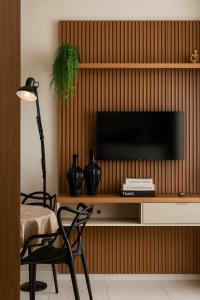 a living room with a television on a wooden wall at Apartamento Frente ao Mar no Embaré Moderno Completo com Vaga in Santos