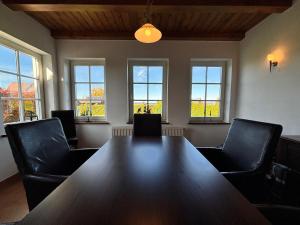 a conference room with a table and chairs and windows at Kranichhaus Boddenblick in Saal