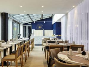 une salle à manger avec tables et chaises et un bar dans l'établissement Mercure Paris la Défense Grande Arche, à Nanterre