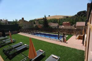 a swimming pool with lawn chairs and umbrellas in a yard at El Rincón de Monasterio in Monasterio