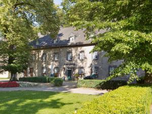duży kamienny dom z drzewami przed nim w obiekcie Romantikhotel Altenberger Hof w mieście Odenthal