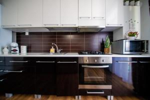 a kitchen with white cabinets and a stove top oven at Penthouse View in Arad