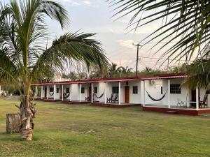 une rangée de bâtiments blancs avec un palmier au premier plan dans l'établissement Villa Agustina en Villas Camino Real cerca de las dunas de Chachalacas, à Ursulo Galván