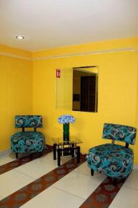twee stoelen en een tafel in een kamer met gele muren bij Hotel Urbane in Mexico-Stad