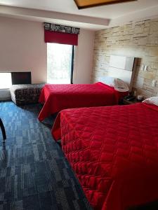 een hotelkamer met 2 bedden en een stenen muur bij Hotel Urbane in Mexico-Stad