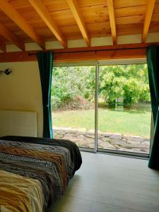a bedroom with a bed and a large window at Réveil au chant des Oiseaux in Chalain-le-Comtal